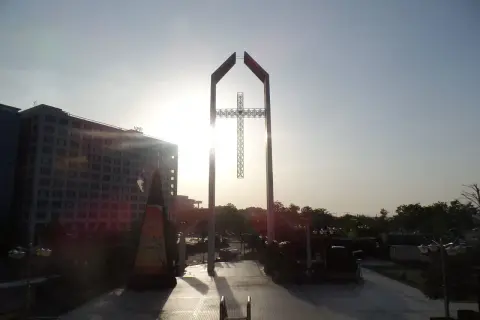 Ein monumentales Kreuz ragt im Gegenlicht empor, ein Symbol der Hoffnung, das mit dem Erbe von David Yonggi Cho verbunden ist.