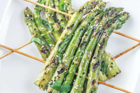 Grillspieße mit Spargel, Sesam und Kräutern auf einem weißen Teller. Perfekt zum Spargel grillen!