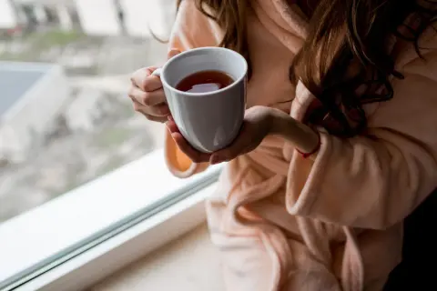 Kobieta w szlafroku trzyma kubek z herbatą. Zastanawiasz się, ile kofeiny ma herbata Earl Grey?