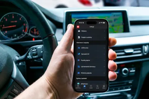 Dłoń trzyma smartfon z aplikacją, gdzie można dokonać **cepik sprawdzenie OC**. W tle widać wnętrze samochodu.