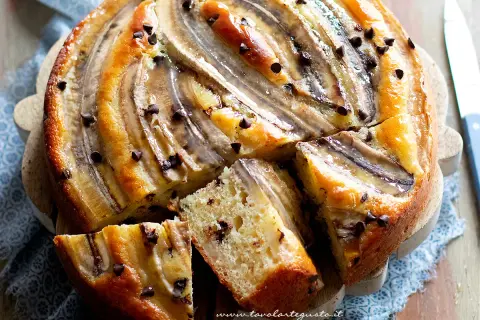Delizioso dolce con banane mature e gocce di cioccolato, una fetta mostra la morbidezza dell'impasto.