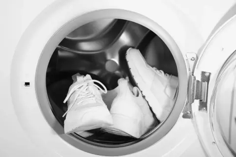 Deux baskets blanches sont prêtes pour leur entretien dans un lave-linge.