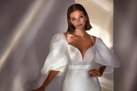 Elegante peinado para damas de boda, con un vestido blanco de escote pronunciado y mangas abullonadas.