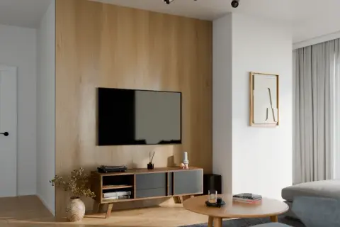 Nowoczesny salon z dominującą ścianą z desek, na której wisi telewizor. Obok stoi komoda z dekoracjami.
