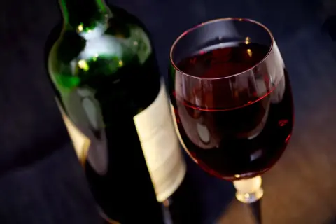Czerwone wino w kieliszku obok butelki. Ile promili po lampce?