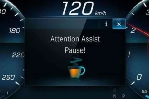 Il display mostra "Attention Assist Pause!" con una tazzina di caffè, indicando come funziona il rilevatore di stanchezza Volkswagen: suggerisce una pausa.