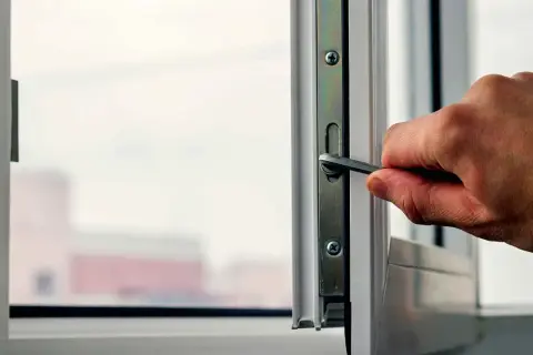 Dłoń używa klucza do regulacji okna, aby dopasować docisk skrzydła.