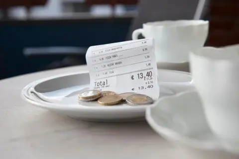 Rechnung mit Münzen auf einem Teller, bereit für das Trinkgeld nach dem Essen auf Sardinien.