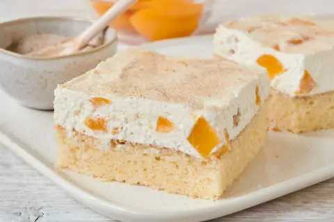 Saftiger Pfirsich Schmand Kuchen mit zarter Sahne und Zimt bestreut. Ein Genuss für jeden Anlass.