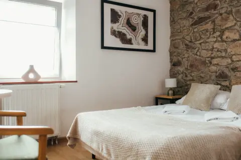 Przytulna sypialnia z kamienną ścianą, łóżkiem i oknem.