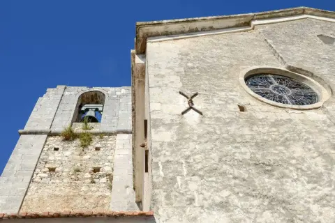 Campanile e rosone di Sant'Elia a Peschici, con il cielo azzurro sullo sfondo.