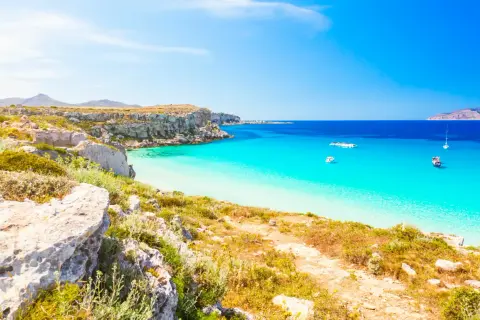 Paesaggio mozzafiato con le calette di Favignana, acque cristalline e barche all'ancora.