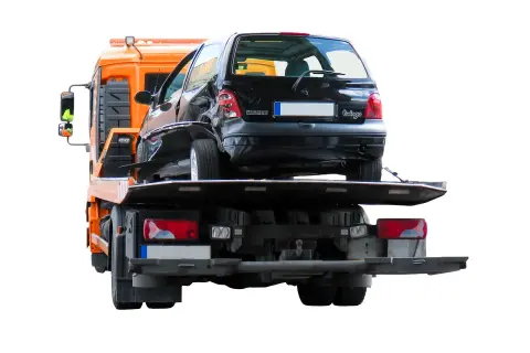 Uszkodzony czarny Renault Twingo jest ładowany na lawetę. Widać, że można holować samochód po wypadku.