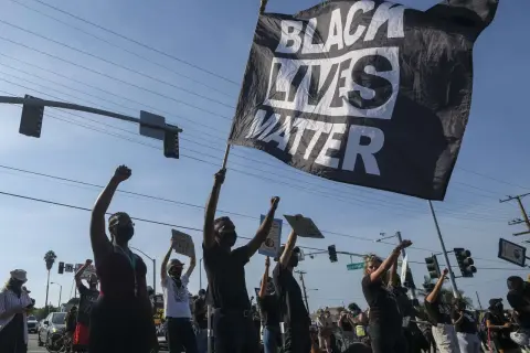 Menschen demonstrieren mit einer "Black Lives Matter"-Flagge. Die Bedeutung von Black Lives Matter ist die Forderung nach Gleichheit und Gerechtigkeit für Schwarze.