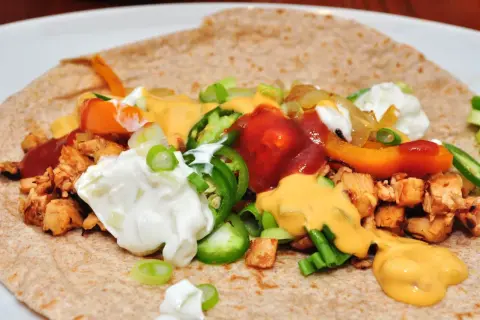 Tortilla garnie de poulet, poivrons, oignons, jalapeños, sauce au fromage et crème aigre. Une délicieuse recette tortilla à déguster !