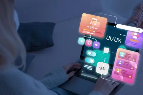 Persona trabajando en el diseño web de una aplicación, con elementos de UI/UX flotando sobre la pantalla.