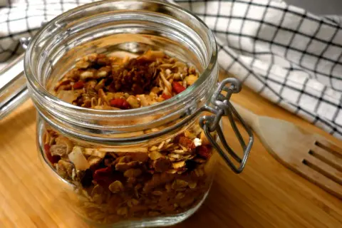 En burk med hemmagjord granola, perfekt som ett bra mellanmål på jobbet. Innehåller nötter, frön och torkad frukt.