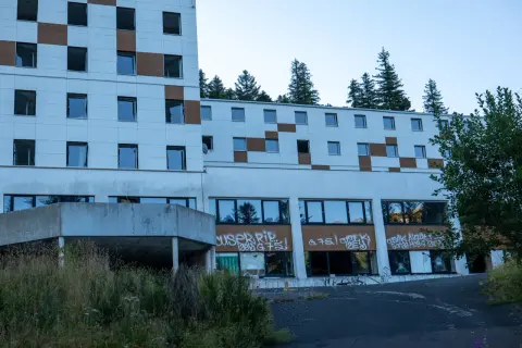 Bâtiment abandonné tagué, vestige d'urbex près du Puy de Dôme. La nature reprend ses droits, fenêtres brisées et végétation envahissante.