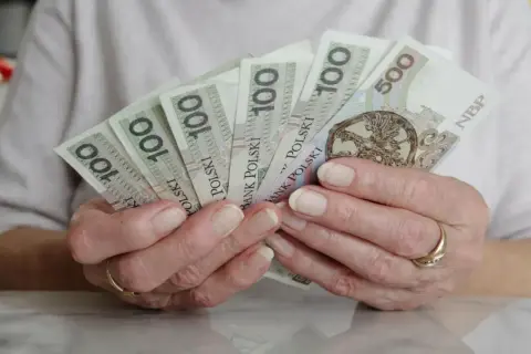 Dłonie trzymają polskie banknoty. Czy mam 60 lat i 10 lat pracy, czy dostanę emeryturę?