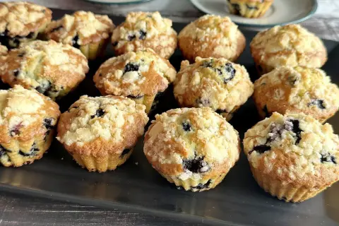 Pyszne muffinki z jagodami, posypane kruszonką, kuszą swoim wyglądem. Idealne na deser lub śniadanie.