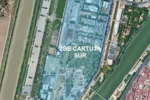 Vista aérea de la zona ZBE Cartuja Sur en Sevilla, delimitada en azul, junto a un río y edificios.