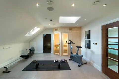 Accogliente palestra in mansarda con vogatore, cyclette, pesi e sauna. Ideale per allenarsi e rilassarsi.