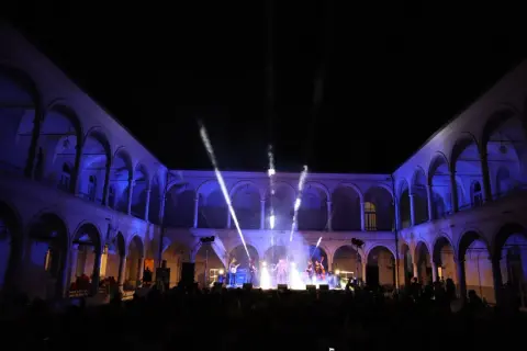 Concerto live sotto gli archi illuminati, un'atmosfera magica per la festa della musica a Brescia.
