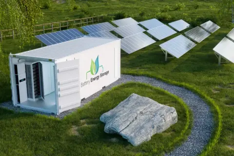 Kontener magazynu energii z bateriami obok paneli fotowoltaicznych na zielonej łące.