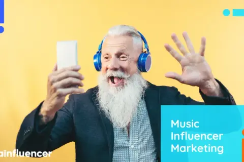 An excited older man with a long white beard wears headphones and holds a phone, ready to share his thoughts on music influencer marketing.