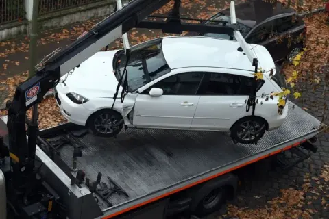 Ein Abschleppdienst hat ein weißes Auto auf einen LKW geladen. Das Auto wurde vorher weggefahren, da es beschädigt war.