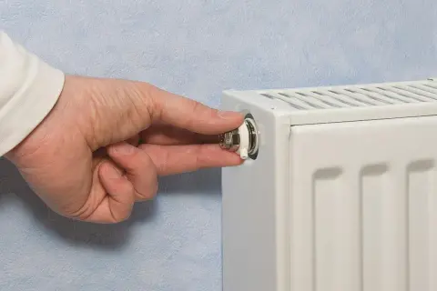 Mano che gira la valvola di uno spurgo termosifone. È il momento di capire quando spurgare i termosifoni per un riscaldamento efficiente.