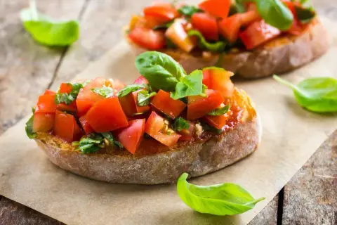 Frische Bruschetta-Rezepte: geröstetes Brot mit Tomaten, Knoblauch und Basilikum, garniert mit Basilikumblättern.