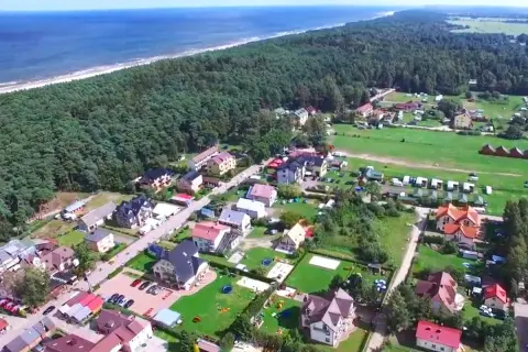 Widok z lotu ptaka na nadmorską miejscowość z domkami i polami namiotowymi. Zastanawiasz się, ile kosztuje nocleg nad morzem?