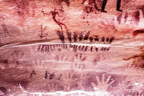Traces de mains et figures humaines stylisées sur la paroi de la grotte de Lascaux, témoins d'une ancienne présence.