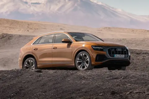 Pomarańczowy Audi Q8 w terenie, gotowy na przygodę. Sprawdź aktualną audi q8 cena i odkryj jego możliwości.