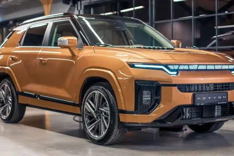 Nowoczesne koreańskie samochody, jak ten pomarańczowy SUV z futurystycznymi światłami, wyznaczają nowe trendy.