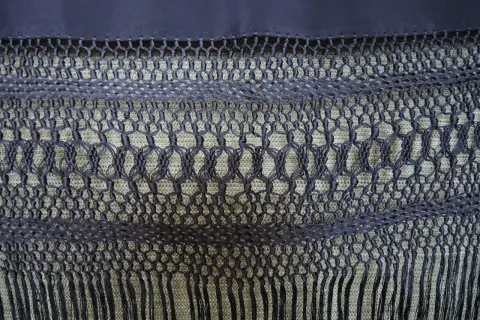 Detalle de cómo hacer flecos para mantones, con un intrincado tejido de macramé y borlas.