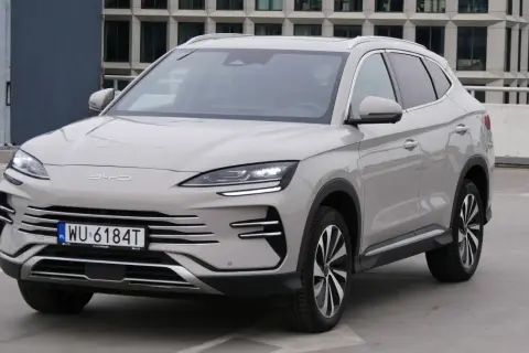 Nowy BYD Song Plus, elegancka hybryda SUV, prezentuje się na parkingu przed nowoczesnym budynkiem.