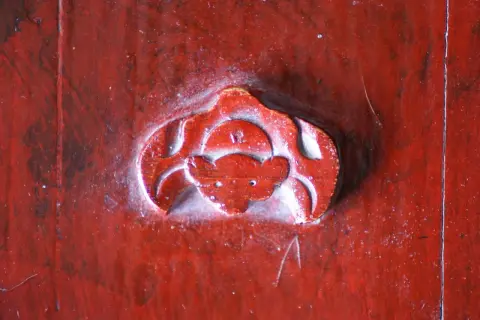 Gravure rouge sur bois, un symbole de chauve-souris, évoquant la chance et la longévité.