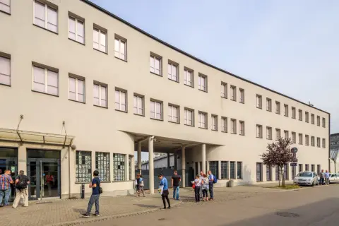 Dawna fabryka Oskara Schindlera w Krakowie, dziś muzeum. Na fasadzie widoczne okna i wejście, przed którym stoją ludzie.