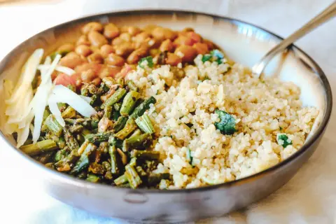 Gesundes Gericht mit Quinoa, Bohnen, grünem Gemüse und Kohlstreifen in einer Schüssel.