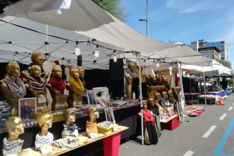Bancarelle colorate alla fiera di Fano, con manichini dorati che indossano sciarpe e foulard.