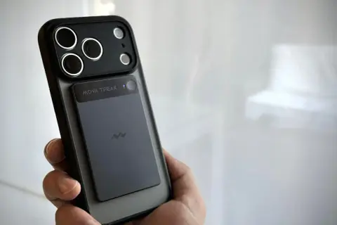 Dłoń trzyma telefon z naklejonym modułem, który może służyć jako dyktafon w telefonie.