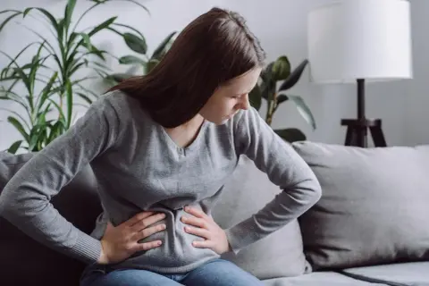 Kobieta z bólem brzucha, być może szukająca ulgi dzięki diecie FODMAP.