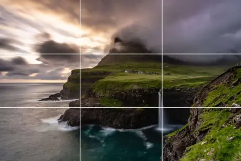 Paysage spectaculaire avec des falaises verdoyantes, une cascade tombant dans l'océan et un village pittoresque. La perspective accentue la beauté sauvage de ce lieu.