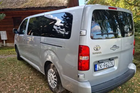 Srebrna Toyota z tablicą ZK 9627K, idealna na cesja leasingu. Zaparkowana przy drewnianym domu z krytym strzechą dachem.
