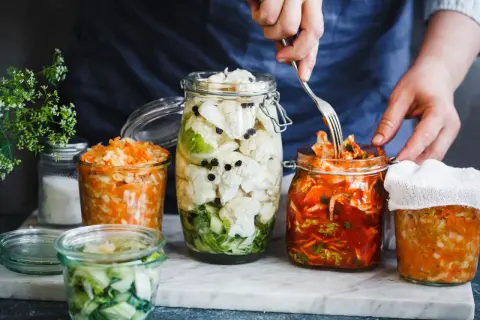 Här är flera burkar med fermenterad mat, inklusive surkål och kimchi, redo att avnjutas.