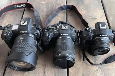 Trzy aparaty Canon EOS R z obiektywami. Jeden z nich, Canon EOS R5, ma obiektyw 24-105mm. Kolejny, Canon EOS RP, wyposażony jest w obiektyw 85mm. Najmniejszy aparat, Canon EOS R50, posiada obiektyw 18-45mm. Wszystkie aparaty mają matrycę APS-C.