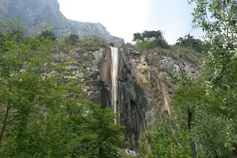 Cascata del Sopino, un velo d'acqua scende da una parete rocciosa circondata da vegetazione lussureggiante.