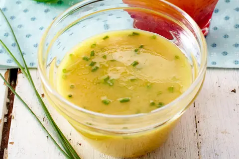Ein Glas mit cremigem honig senf dressing, garniert mit Schnittlauch. Perfekt für Salate.